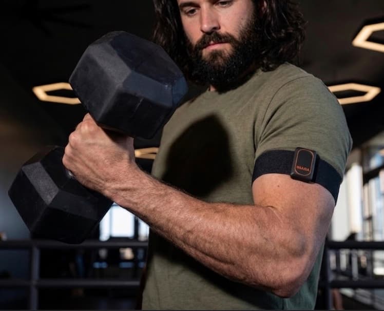 Athlete doing a dumbbell curl while wearing the Inara sensor on an arm band.